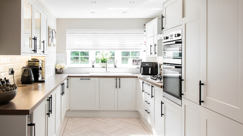 Small U-shaped kitchen with modern white cabinetry and sleek appliances