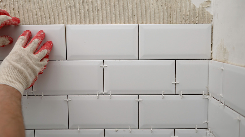 Person placing kitchen backsplash tile on wall