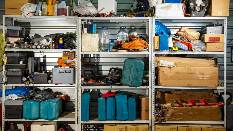 A cluttered garage with standing shelving.