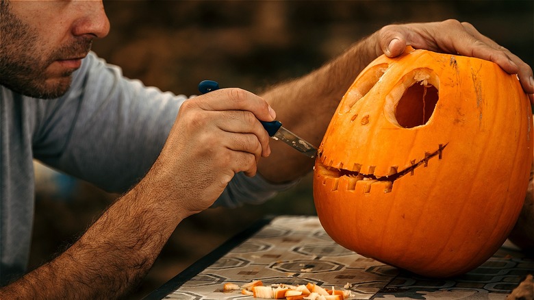 person carving pumpkin