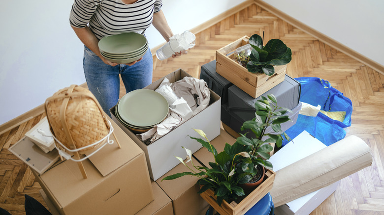 Woman packing decorations into boxes, holding green plates