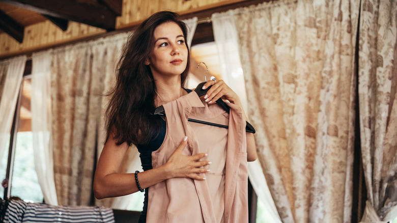 Woman trying on outfits while organizing wardrobe