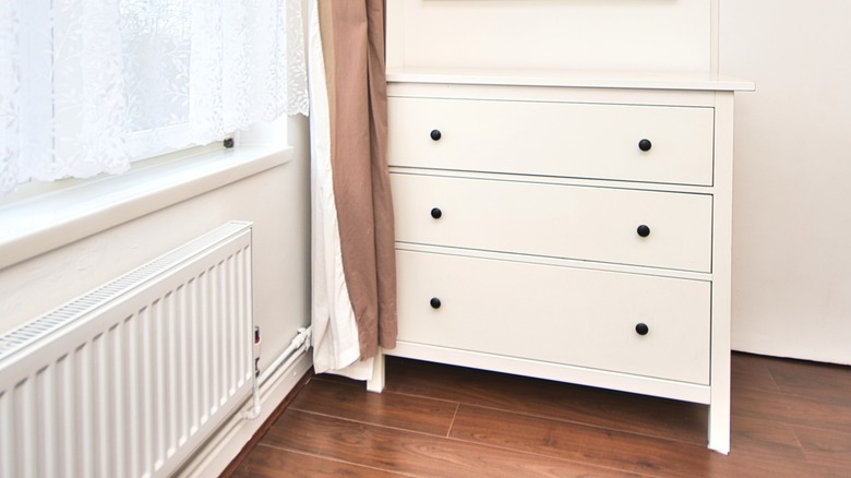 White IKEA three-drawer chest in corner next to bedroom window