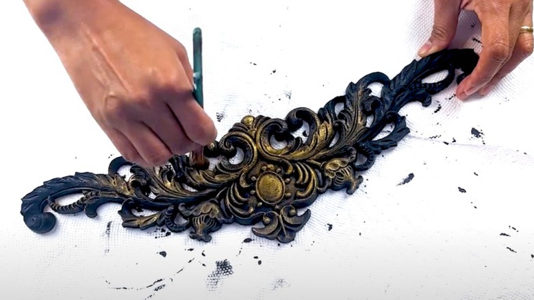 Woman painting applique black and gold over paper towels