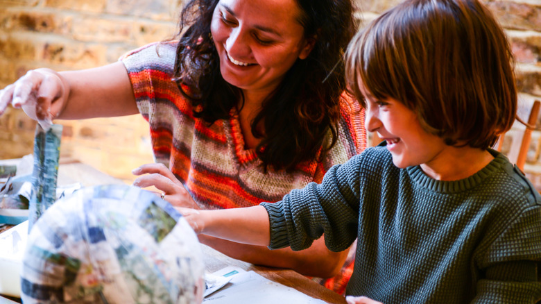 Mother and son making a papier mache elephant.