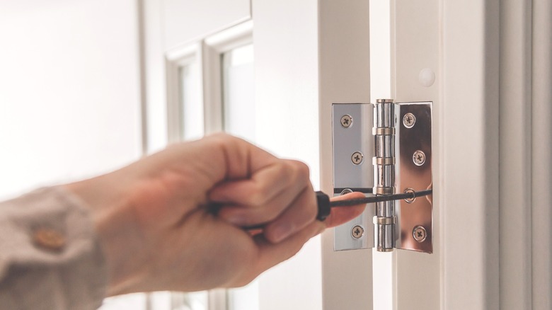 A person screws an interior door hinge