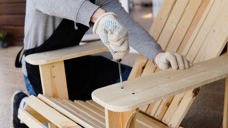 A person is placing a screw into a wooden furniture