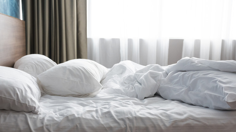 An unmade bed has indentations in the sheets or mattress and multiple pillows