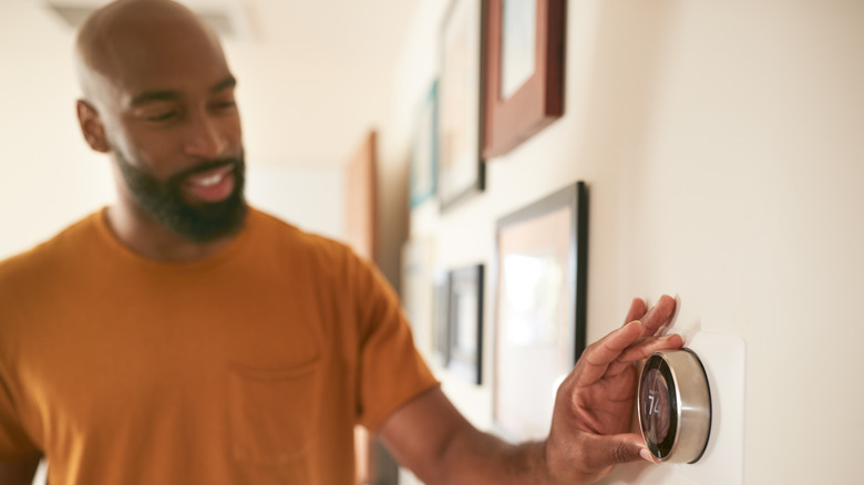 man adjusting home thermostat