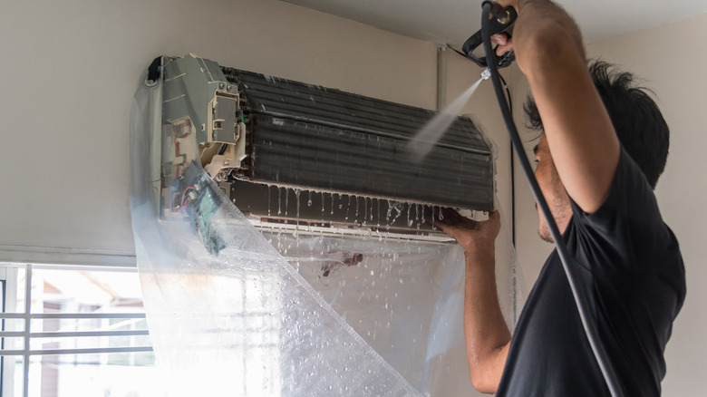 Worker cleaning AC unit