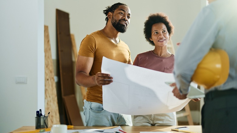 Couple looking at blueprints with contractor