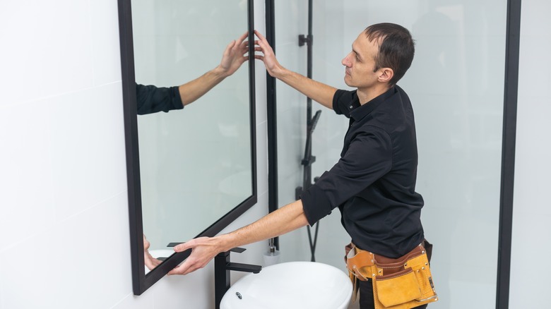 man installing bathroom mirror