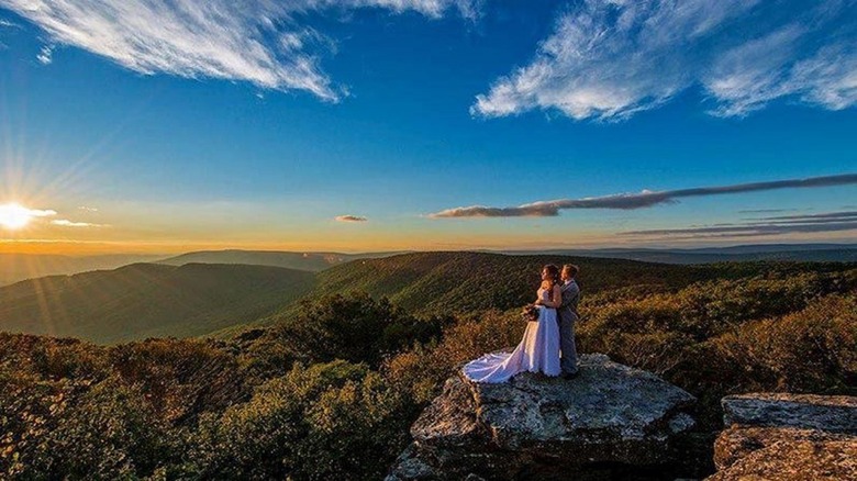 newly weds posing on a high rock