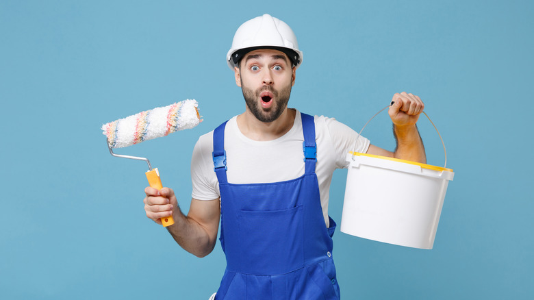 man holding bucket of paint