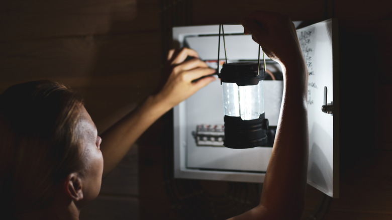 woman with lamp checking fusebox 