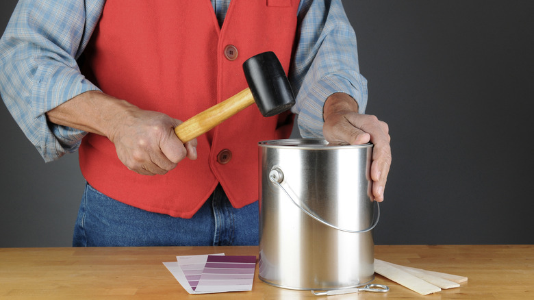 man using mallet on can