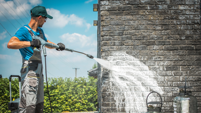 Man pressure washing brick