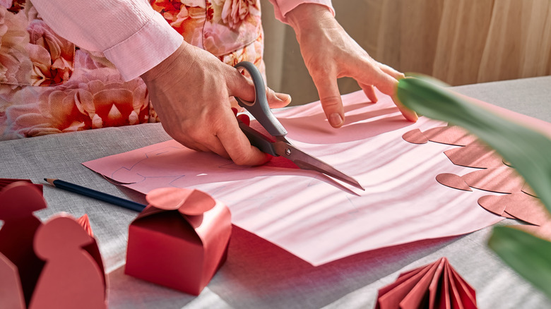 Woman cutting a piece of pink paper.