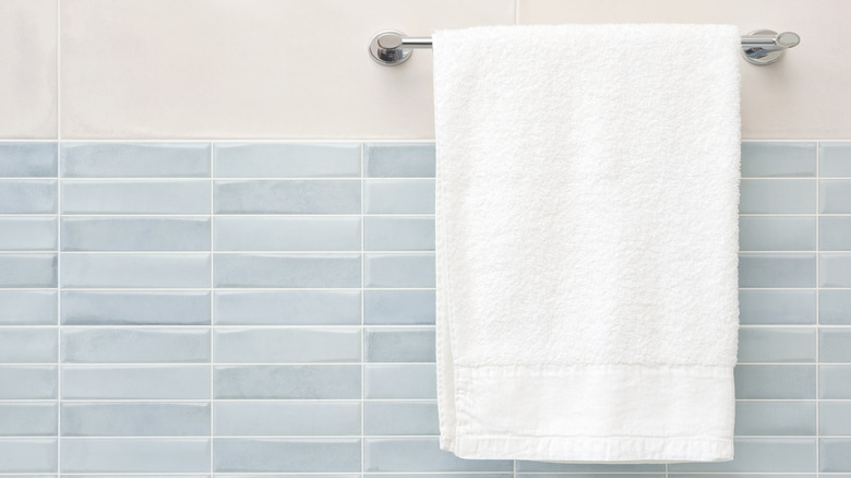 A towel hangs from a rack in a blue and white tiled bathroom