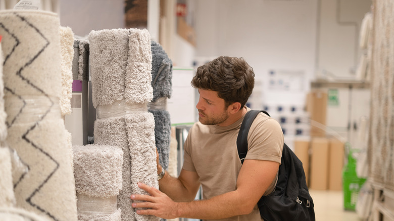 Man shopping for rugs in store