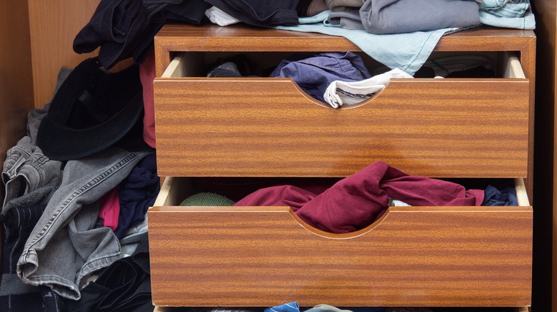 Wooden dresser drawers overflowing with clothes