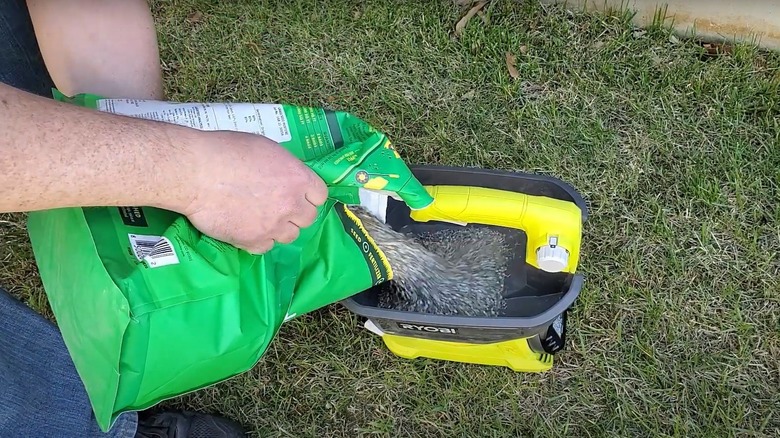 person filling Ryobi spreader with grass seed