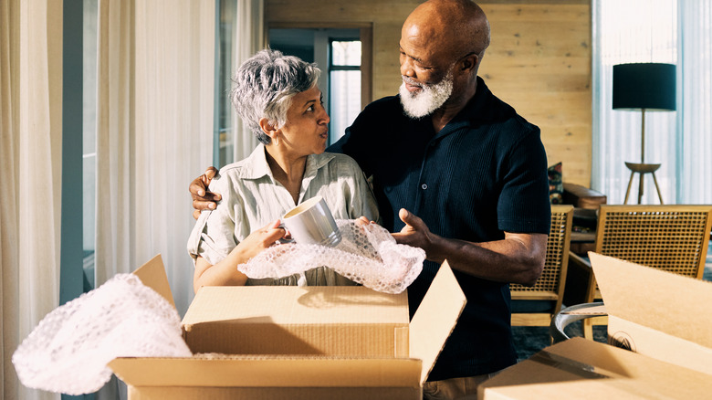 Older man and woman couple packing boxes of dishes