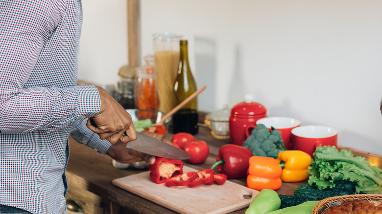 A person uses a knife to cut peppers