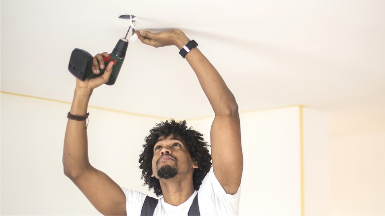 Person drilling hole in ceiling