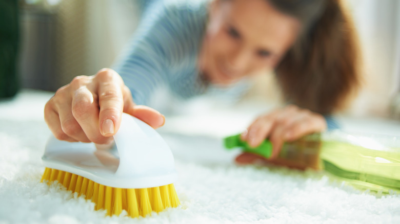 Woman scrubs carpet with brush