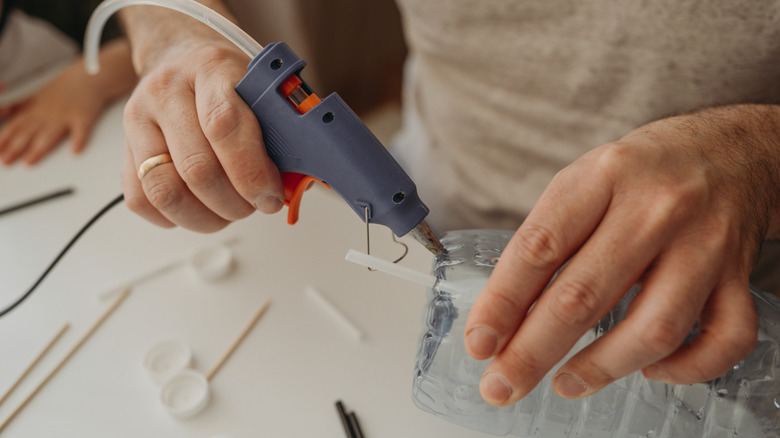 A person is using glue gun to do a craft