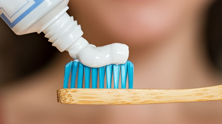 Person applying toothpaste on brush