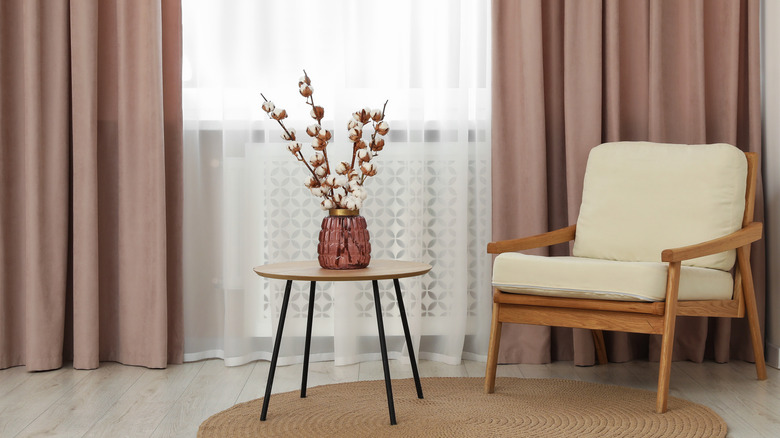 Pink curtains behind wood chair and table