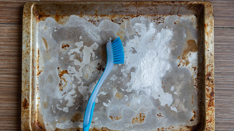 Scrub brush on dirty baking sheet