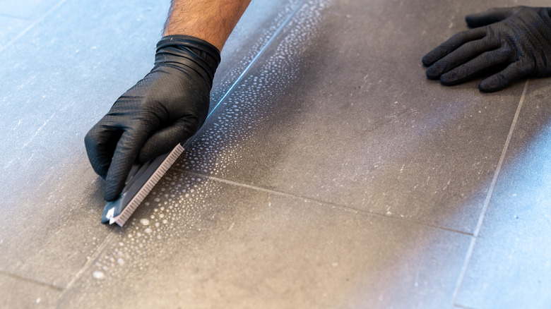 Cleaning grout lines with brush.