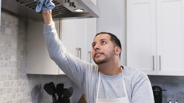 Man wiping down kitchen range hood