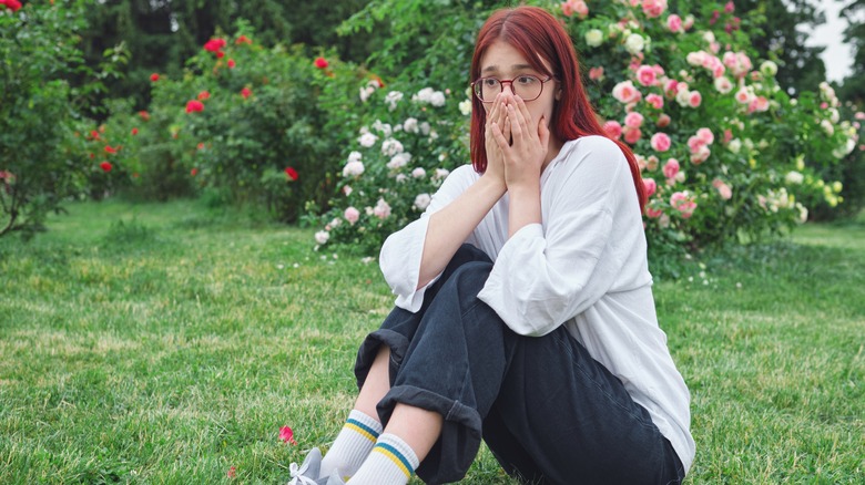 woman holding nose lawn outside