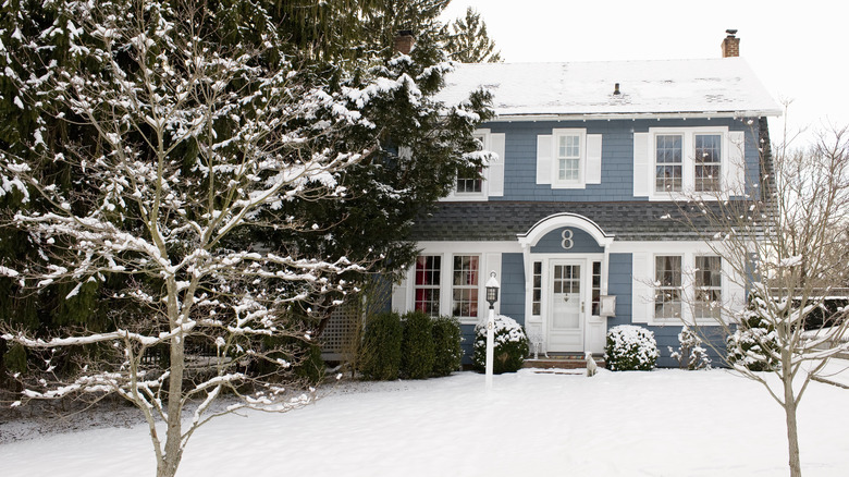 A blue home in the winter surrounded by snow.