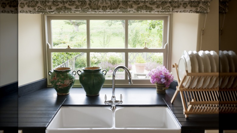 A window over a farmhouse sink overlooks a cottage garden