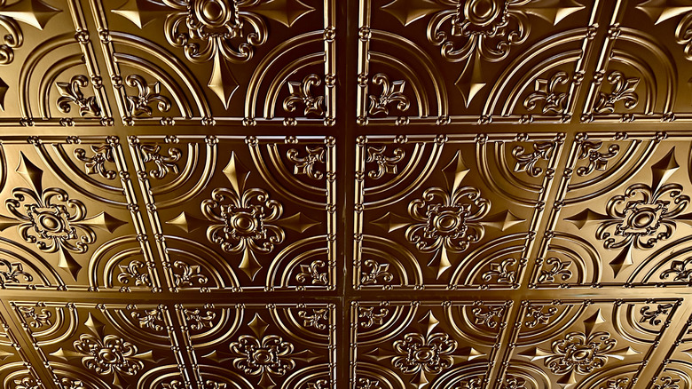 Intricate bronze-colored ceiling tiles reflecting light