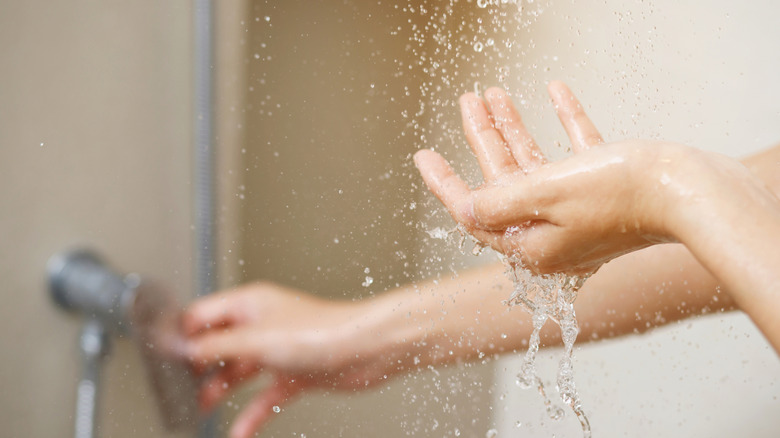 A person testing the shower temperature