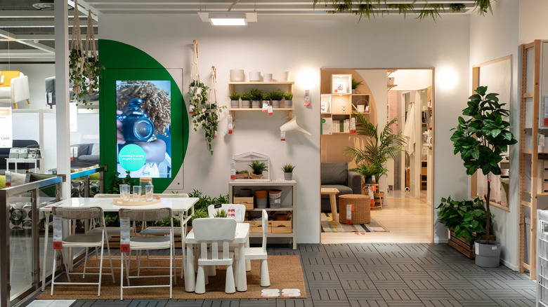 An IKEA store displaying fake plants, pots, and a dining display