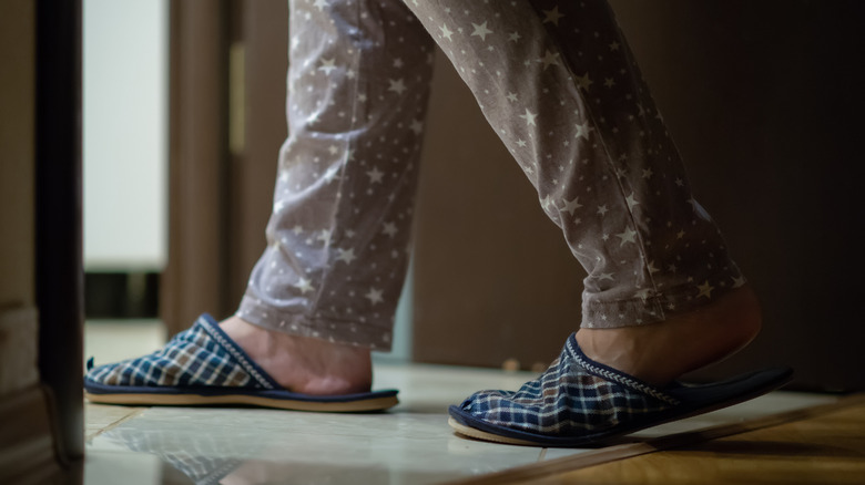 A person's feet in slippers walking into the bathroom at night