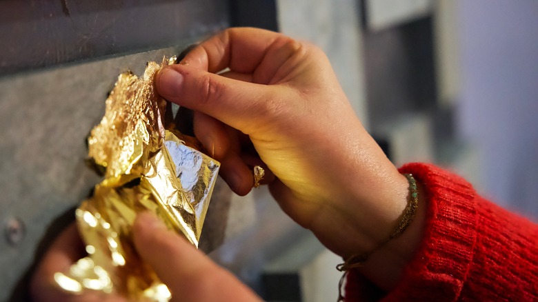 person working with gold leaf