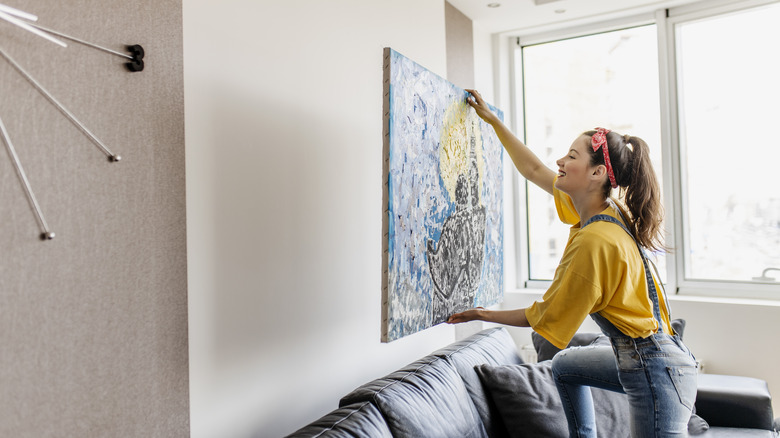 woman hanging large artwork