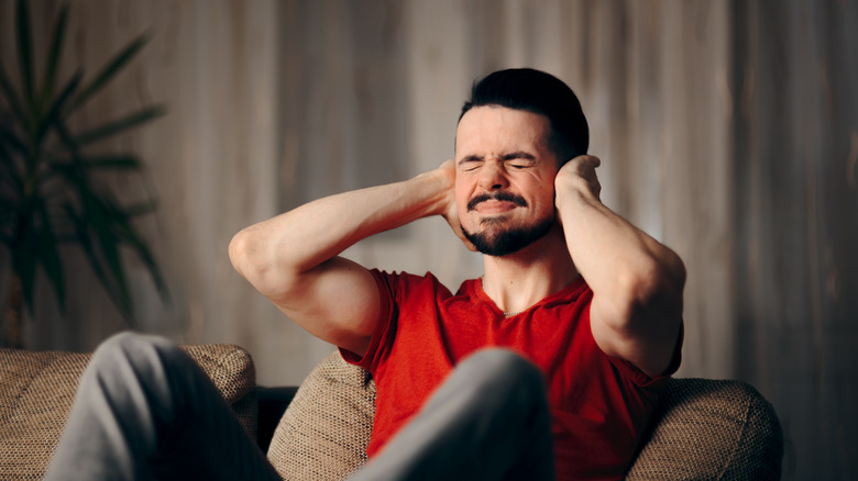 man reacts to loud noise