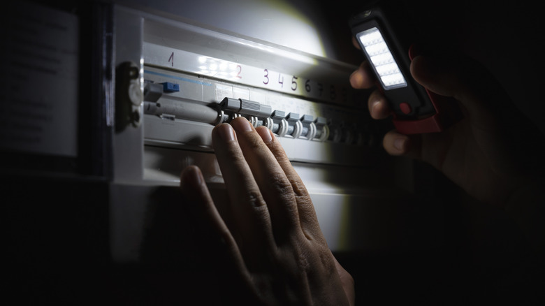 Person examining fuse box in blackout