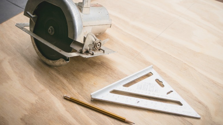 circular saw, speed square, and pencil sitting on plywood sheet