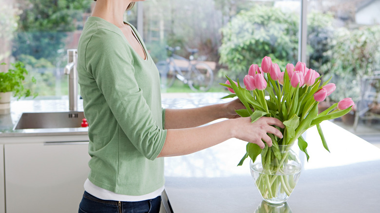 Woman styles flowers in vase