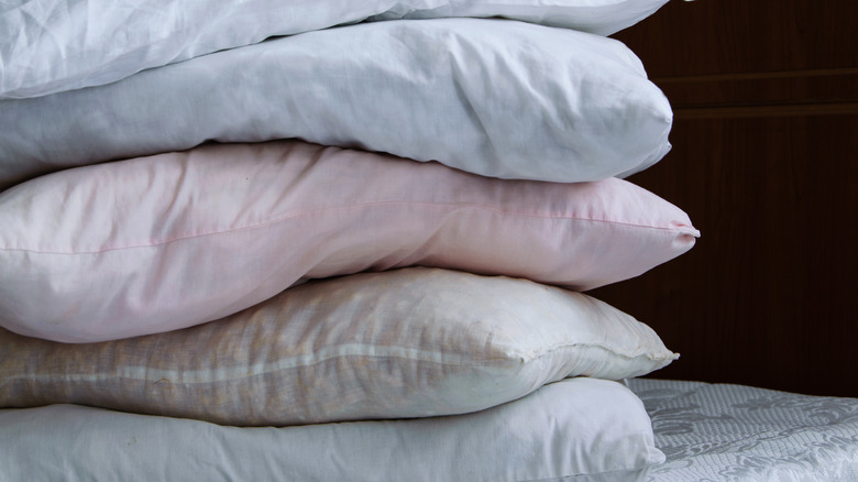 stack of used bed pillows on mattress